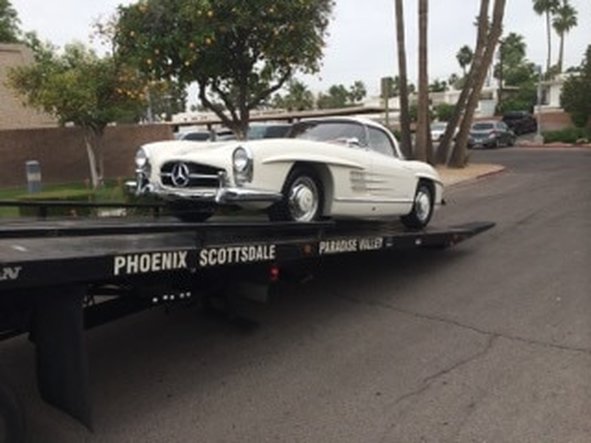 Flatbed tow truck with classic Mercedez Benz loaded on back