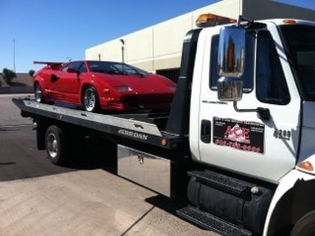 White tow truck with red Lamborghini on back