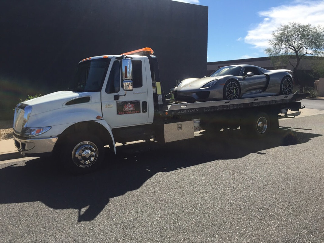 White tow truck with exotic car on flatbed